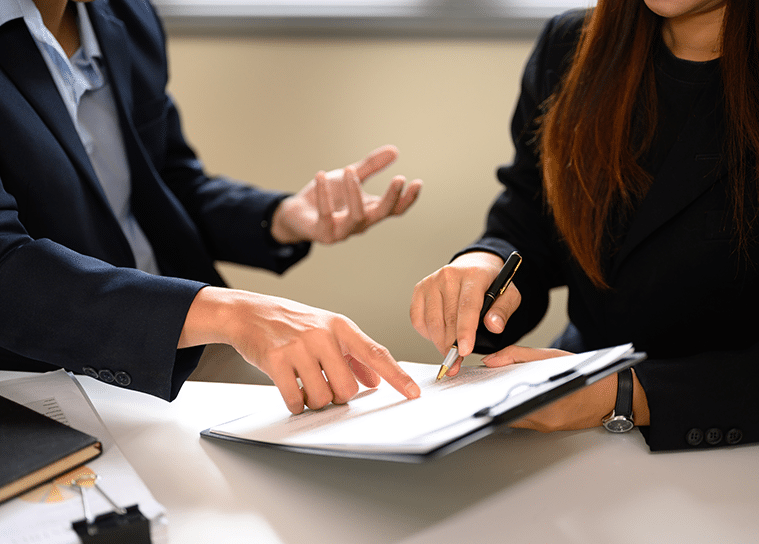 Attorney pointing at legal contract document for client signature during consultation